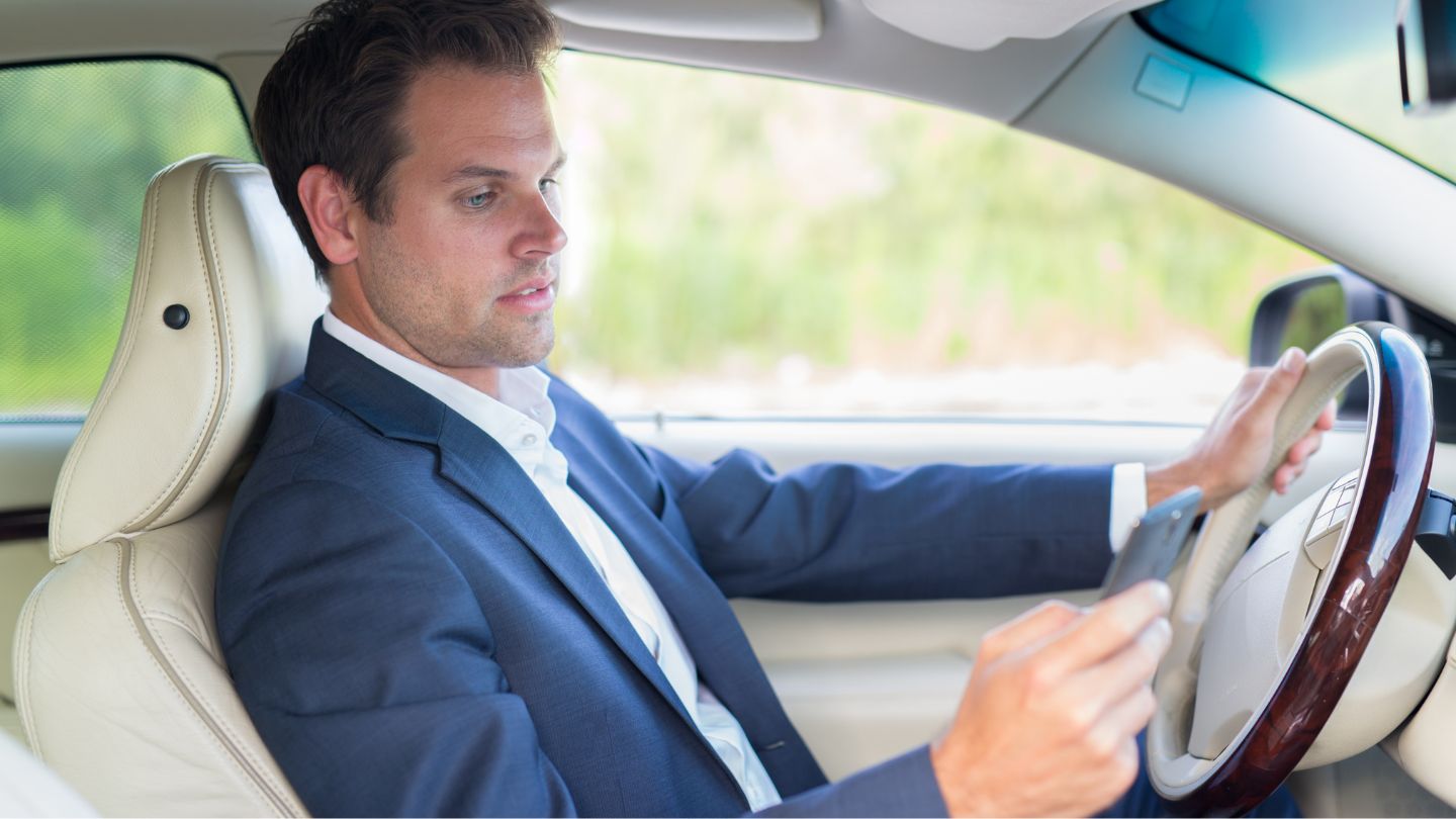 Man In A Suit Using A Cell Phone While Driving.