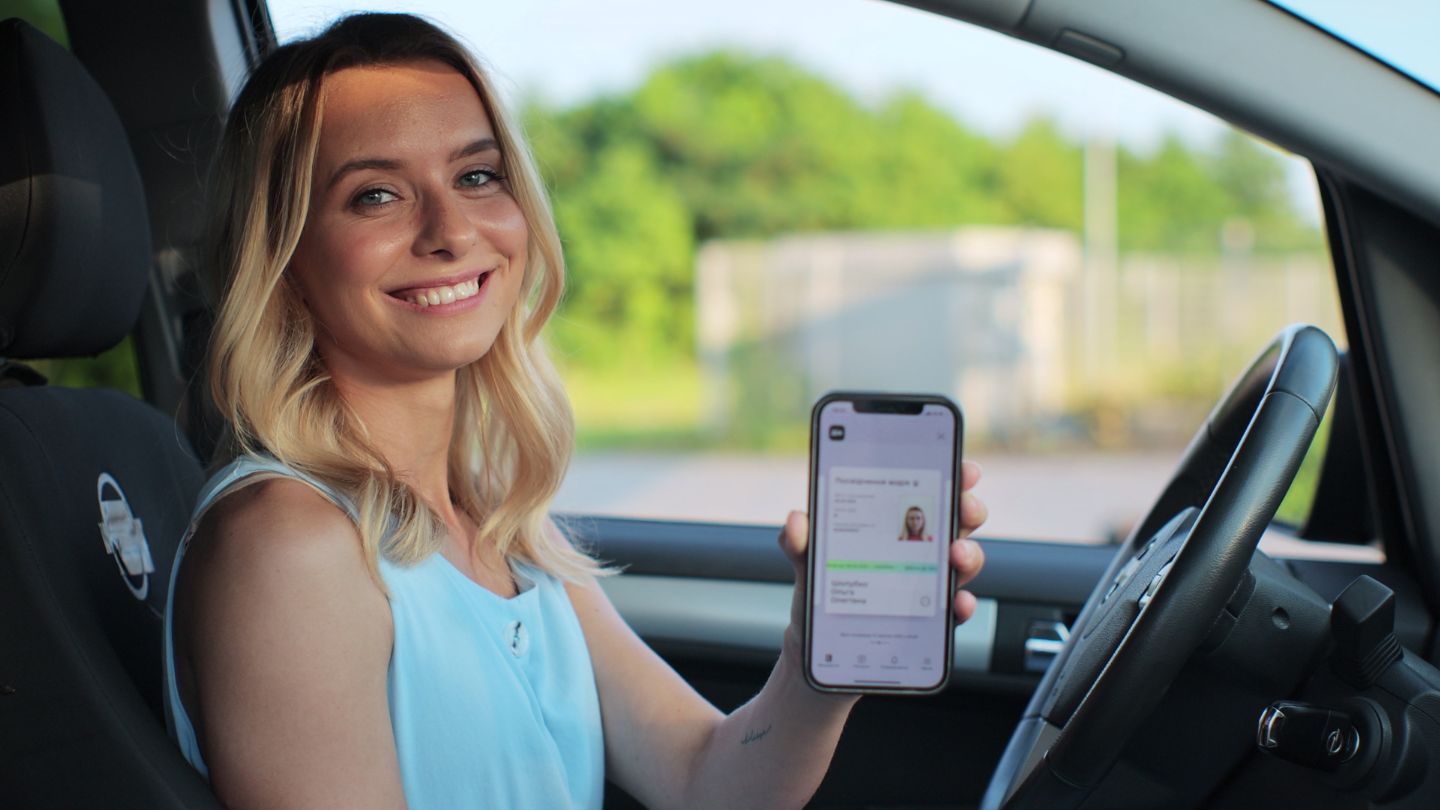 Smiling Woman In Car Holding Up A Smartphone.