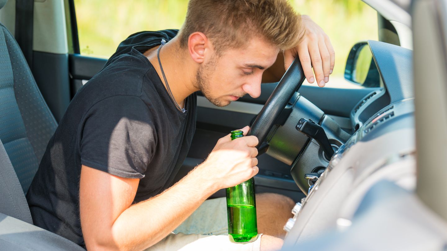 Man Holding Alcohol Bottle While Driving