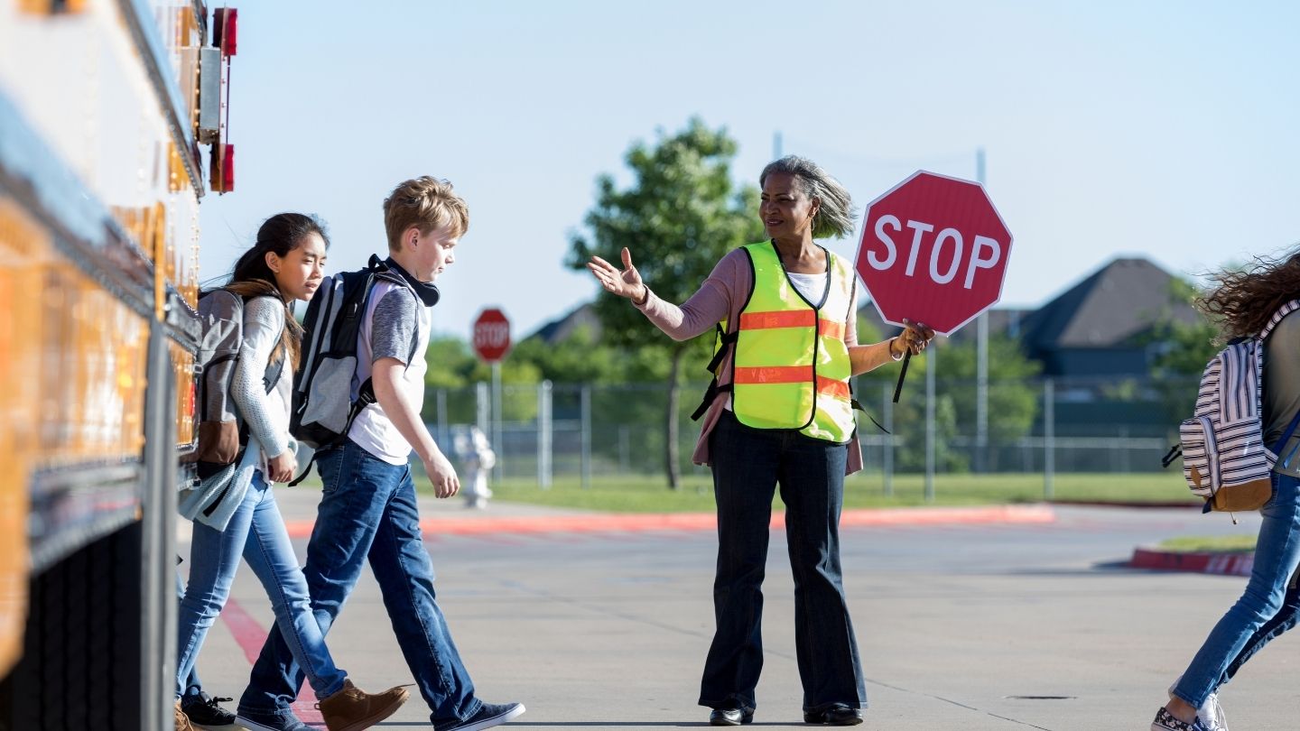 Crossing Guard Holding Stop Sign With Children 