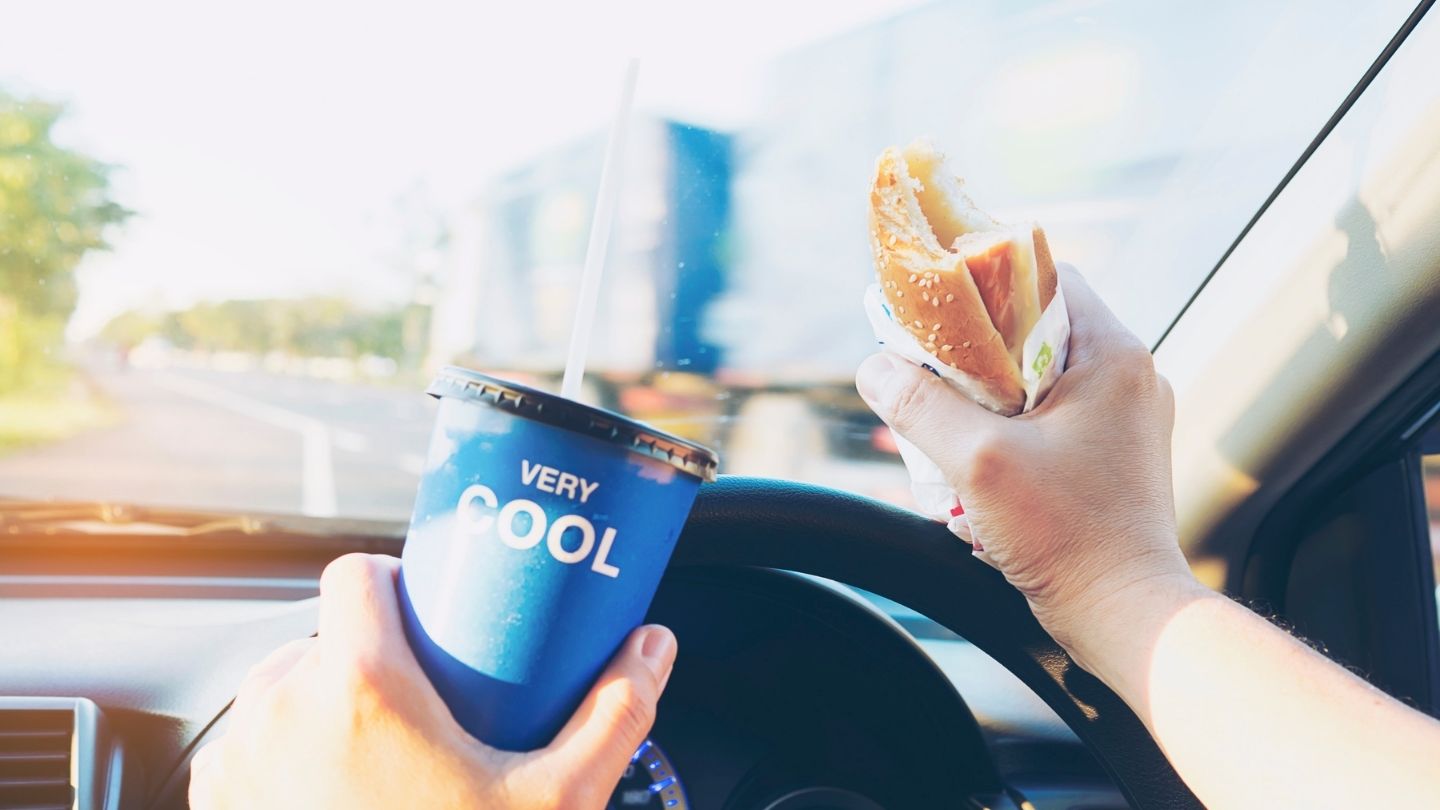 Driver Holding Food And A Drink While Driving
